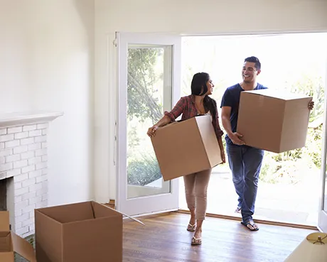 couple carrying moving boxes into new home