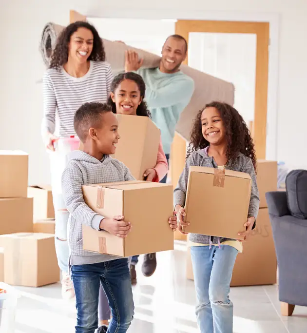 a young family of five carrying moving boxes and smiling