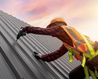 photo of a contractor in a hard hat and safety vest installing a roof
